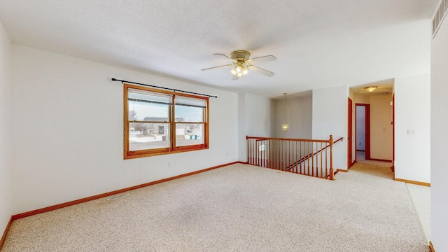 carpeted spare room featuring visible vents, ceiling fan, a textured ceiling, and baseboards