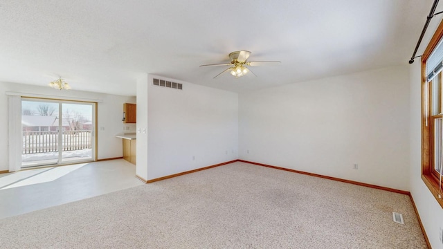 unfurnished room featuring visible vents, light colored carpet, baseboards, and ceiling fan