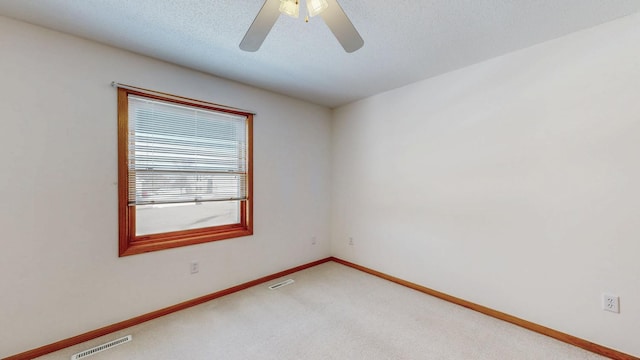 unfurnished room with a textured ceiling, light colored carpet, visible vents, and baseboards