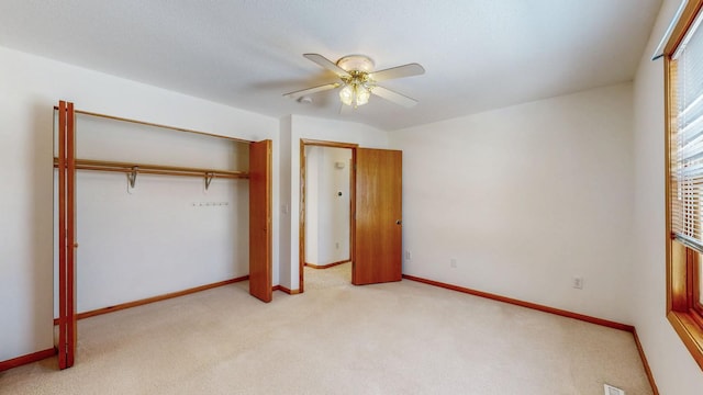 unfurnished bedroom featuring a closet, light colored carpet, a ceiling fan, and baseboards