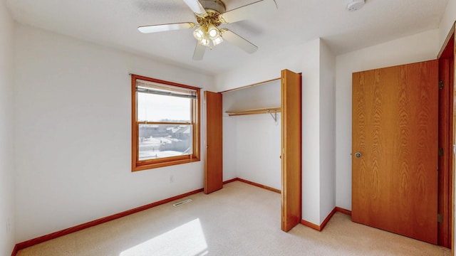 unfurnished bedroom with a ceiling fan, visible vents, baseboards, a closet, and light carpet