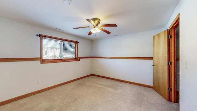 spare room with light colored carpet, a ceiling fan, and baseboards