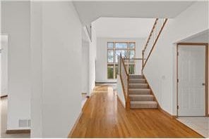 foyer with visible vents, stairway, and wood finished floors