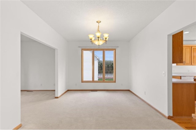 empty room with light carpet, visible vents, baseboards, an inviting chandelier, and a textured ceiling