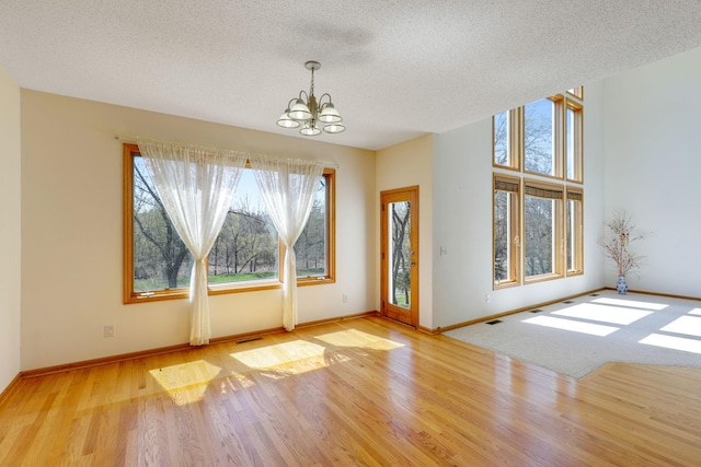 entrance foyer with wood finished floors, visible vents, a textured ceiling, and an inviting chandelier