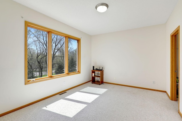 unfurnished room with visible vents, light carpet, and baseboards