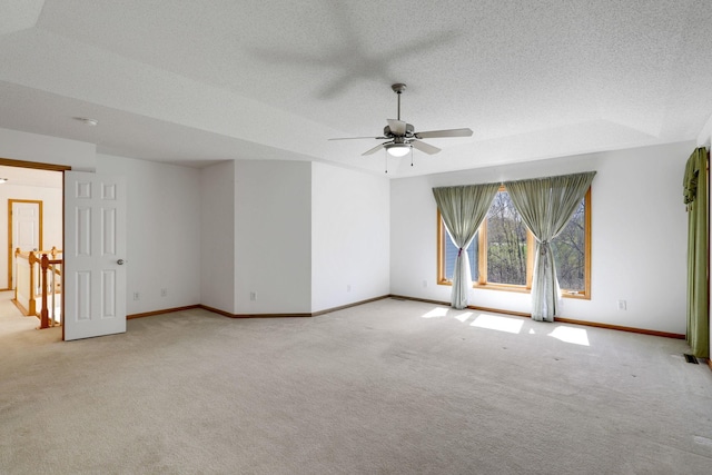 empty room featuring ceiling fan, baseboards, a textured ceiling, and light colored carpet