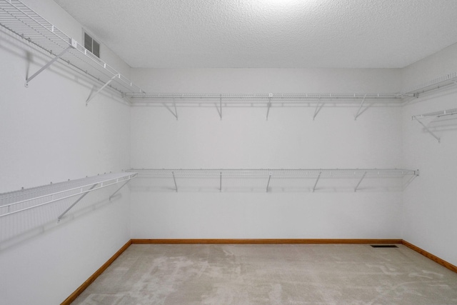 walk in closet featuring light carpet and visible vents