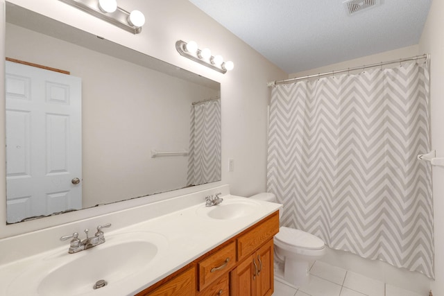 bathroom with double vanity, tile patterned flooring, a sink, and toilet