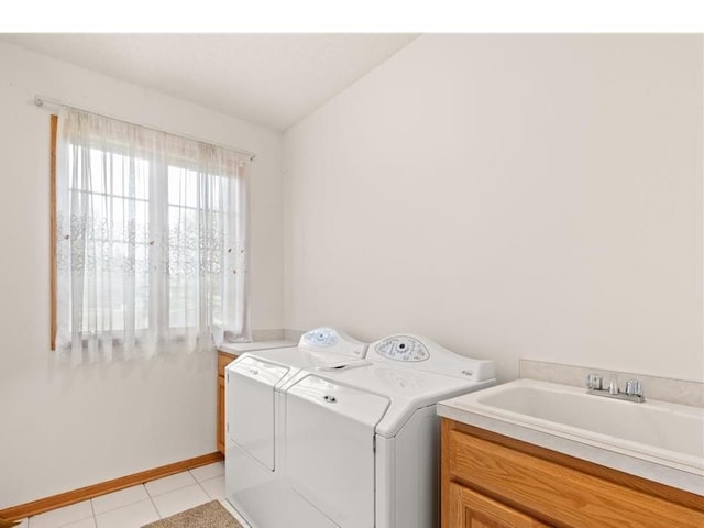 washroom with washing machine and clothes dryer, cabinet space, light tile patterned flooring, a sink, and baseboards