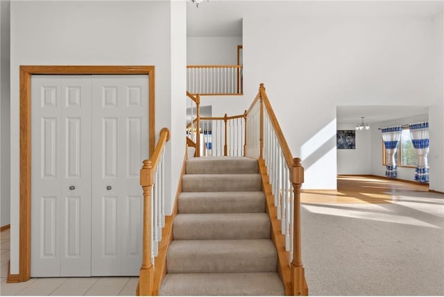 stairway with carpet floors, tile patterned flooring, and a notable chandelier