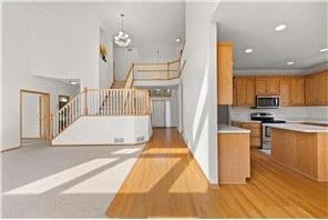 kitchen with a notable chandelier, stainless steel appliances, light wood-style floors, light countertops, and brown cabinetry