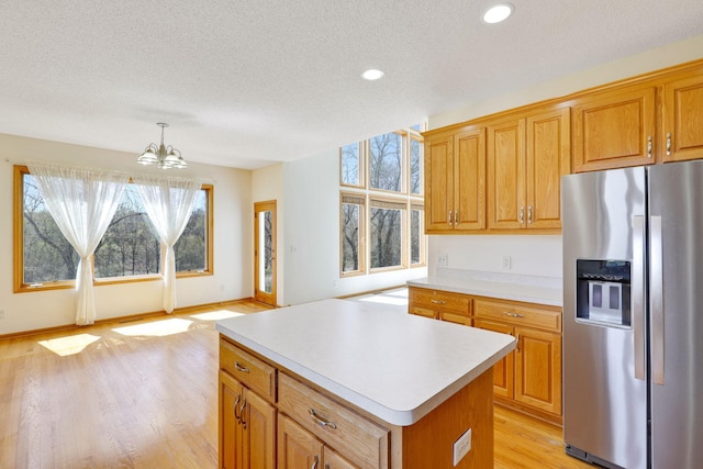 kitchen with a textured ceiling, a chandelier, light wood finished floors, light countertops, and stainless steel fridge with ice dispenser