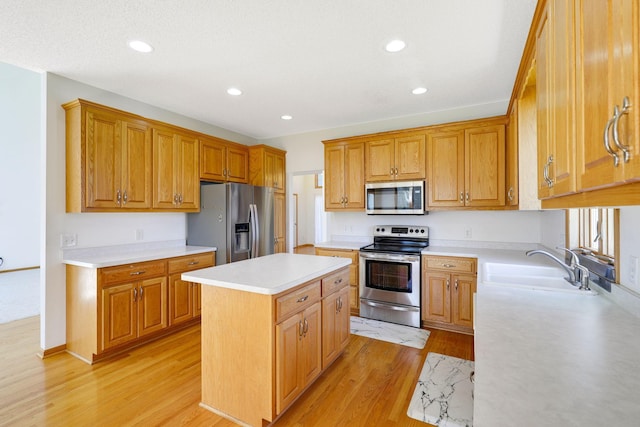 kitchen featuring a sink, stainless steel appliances, light wood finished floors, light countertops, and a kitchen island