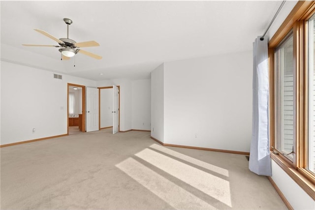 empty room featuring light colored carpet, baseboards, and a ceiling fan