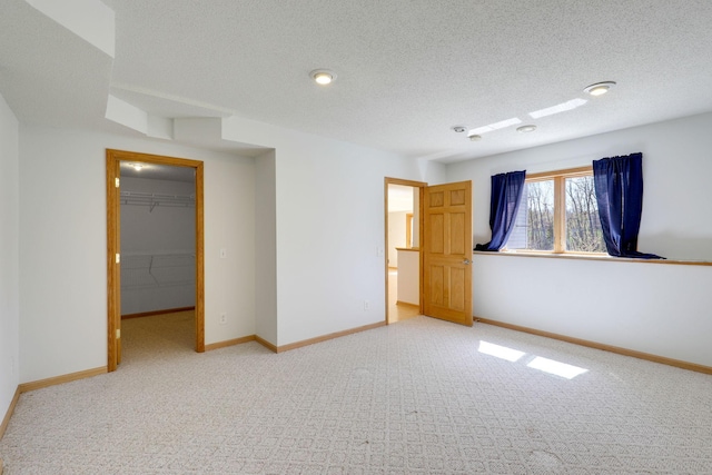 empty room featuring a textured ceiling, carpet, and baseboards