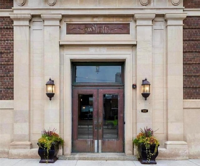 entrance to property featuring stone siding, french doors, and brick siding