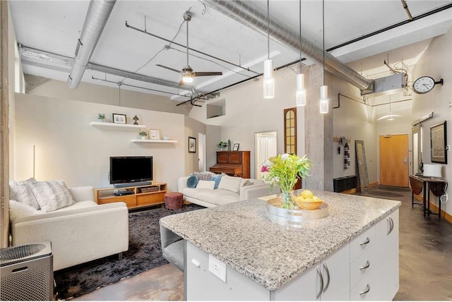 kitchen with a center island, light stone countertops, a towering ceiling, and finished concrete flooring