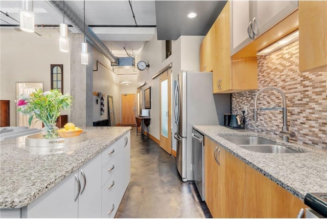 kitchen featuring stainless steel appliances, light stone counters, a sink, and a towering ceiling