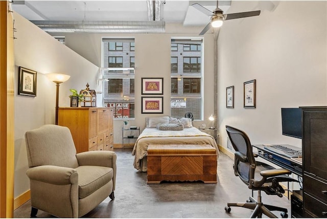 bedroom with finished concrete flooring, a high ceiling, and baseboards