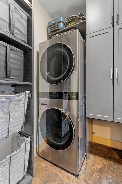 clothes washing area with cabinet space and stacked washer / drying machine