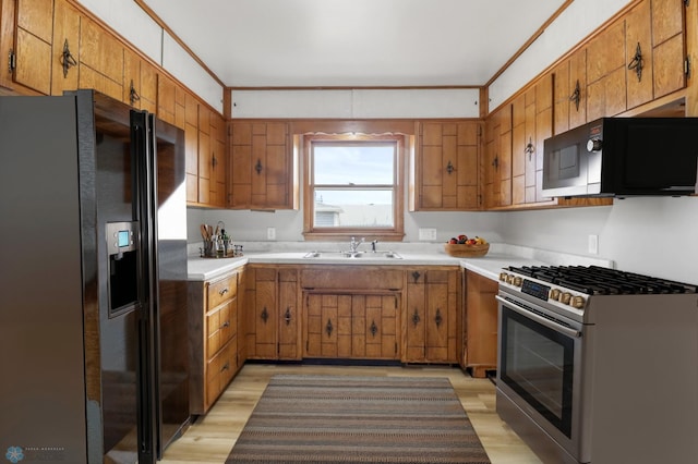 3129 7th St N, Fargo, ND 58102 - kitchen featuring black appliances, a sink, brown cabinets, light wood-type flooring, and light countertops