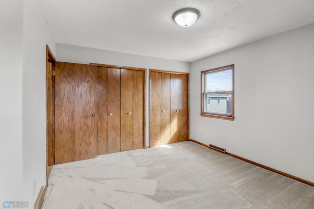 3129 7th St N, Fargo, ND 58102 - unfurnished bedroom featuring carpet floors, multiple closets, baseboards, and a textured ceiling