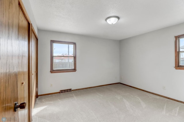 3129 7th St N, Fargo, ND 58102 - unfurnished bedroom featuring light carpet, baseboards, a textured ceiling, and a closet