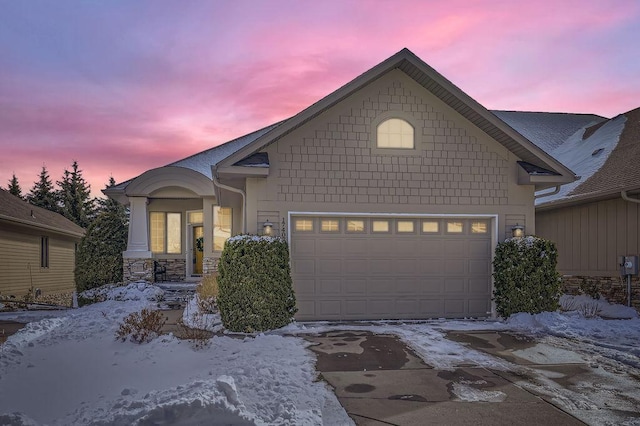 view of front of home with a garage, stone siding, and driveway