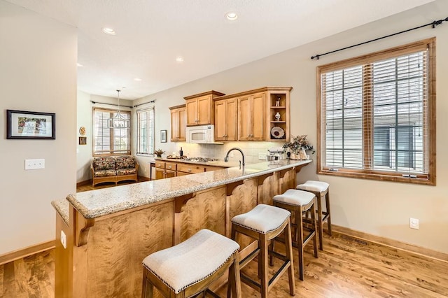 kitchen featuring white appliances, tasteful backsplash, a kitchen bar, and open shelves