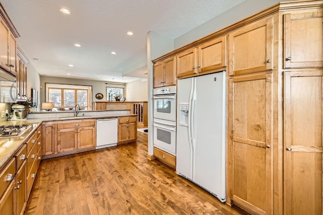 kitchen with stainless steel appliances, recessed lighting, a sink, wood finished floors, and a peninsula