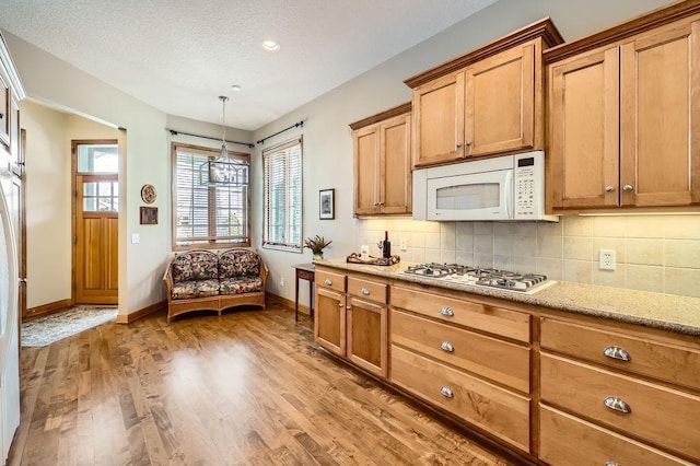 kitchen with white appliances, baseboards, light wood-style flooring, light stone counters, and backsplash