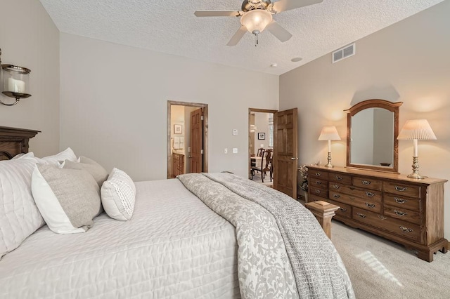 bedroom featuring visible vents, light carpet, ceiling fan, a textured ceiling, and ensuite bath