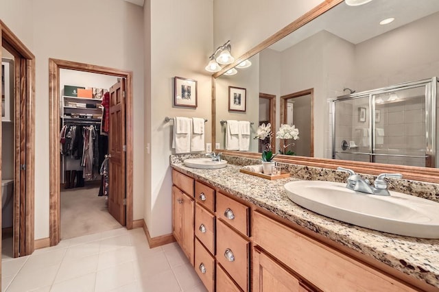 bathroom featuring double vanity, a shower stall, a spacious closet, and a sink