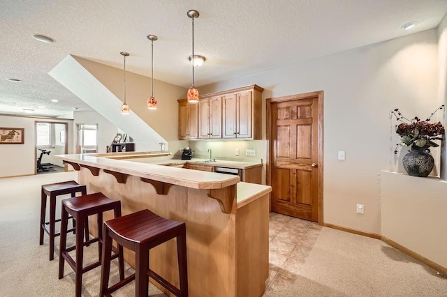 kitchen with a breakfast bar area, decorative light fixtures, a peninsula, light countertops, and a textured ceiling