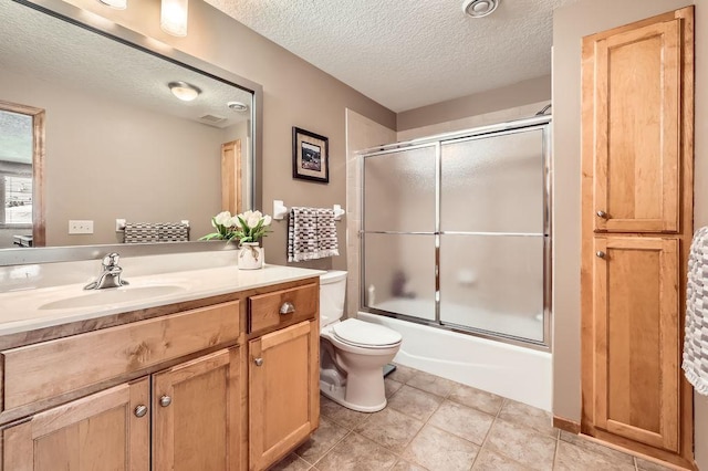 bathroom with a textured ceiling, tile patterned flooring, toilet, bath / shower combo with glass door, and vanity