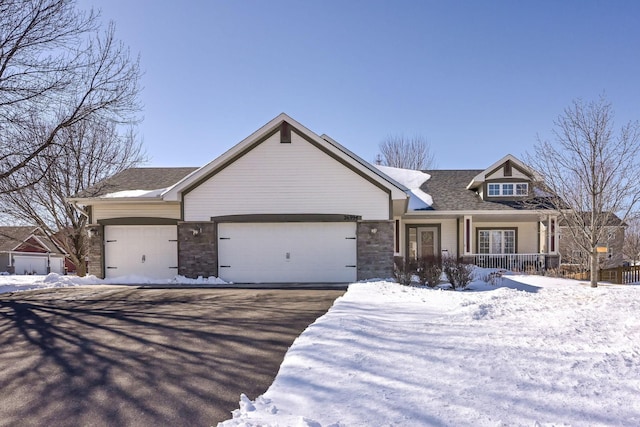 view of front of house with stone siding, driveway, roof with shingles, and an attached garage