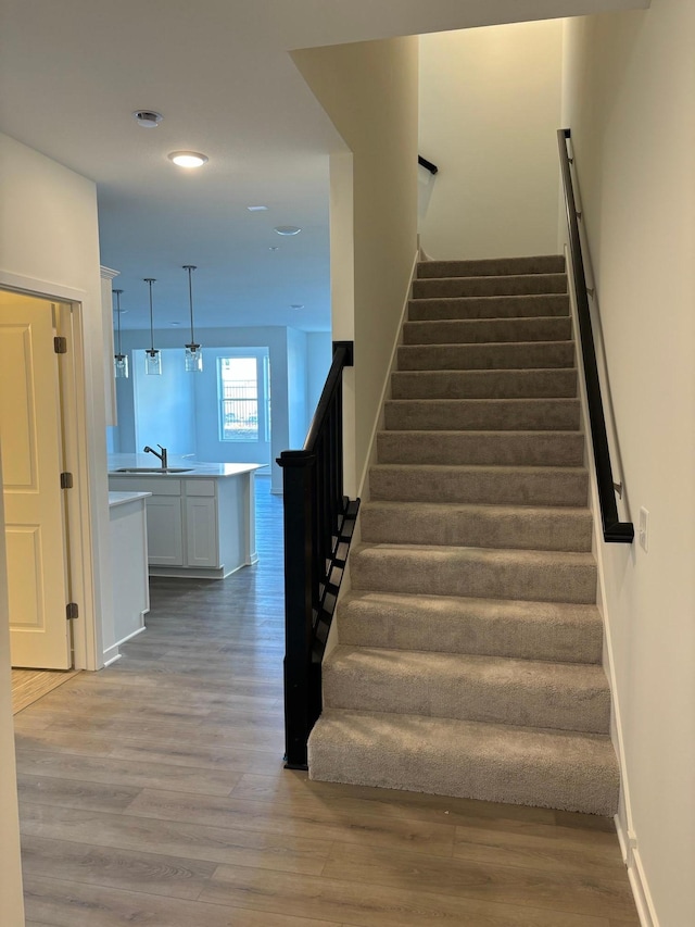 stairs with recessed lighting, wood finished floors, and baseboards