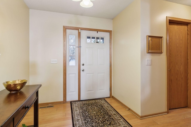 entryway with visible vents, light wood-style flooring, and baseboards