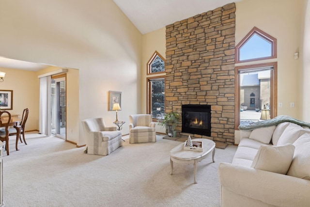 carpeted living room with a chandelier, high vaulted ceiling, a stone fireplace, and baseboards