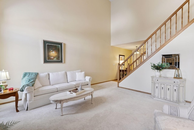 living area featuring carpet floors, a towering ceiling, baseboards, and stairs