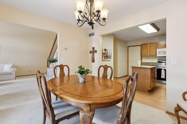 dining room with a chandelier, light colored carpet, visible vents, and baseboards