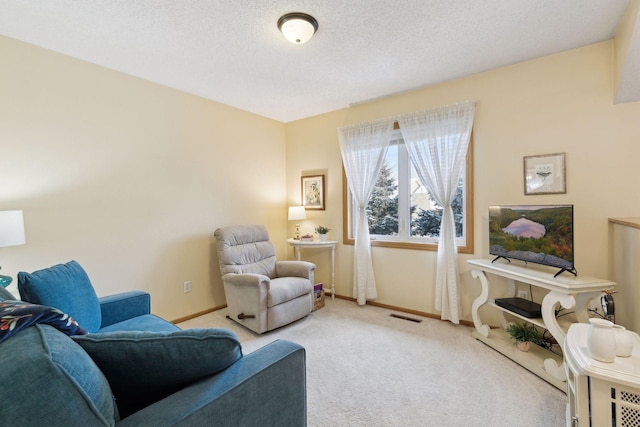 sitting room featuring carpet flooring, visible vents, baseboards, and a textured ceiling