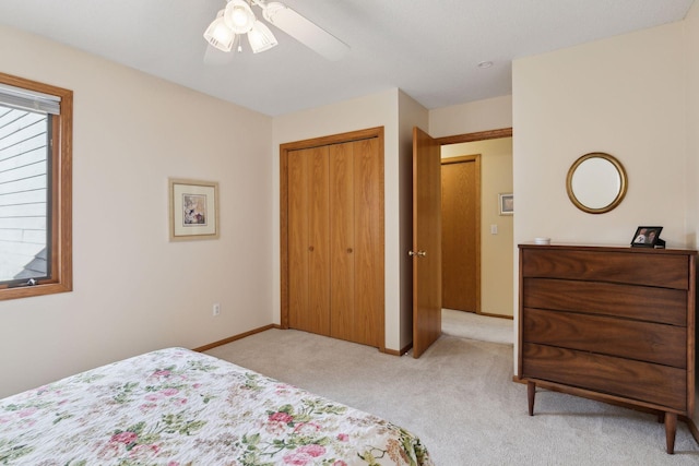 bedroom featuring light carpet, ceiling fan, a closet, and baseboards