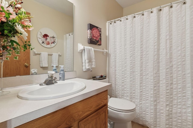 bathroom featuring curtained shower, vanity, and toilet