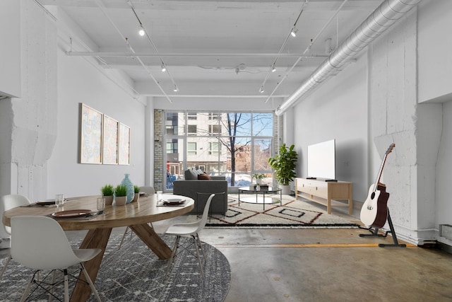 dining room featuring rail lighting and concrete flooring