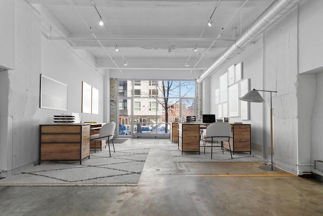 office featuring rail lighting and unfinished concrete flooring