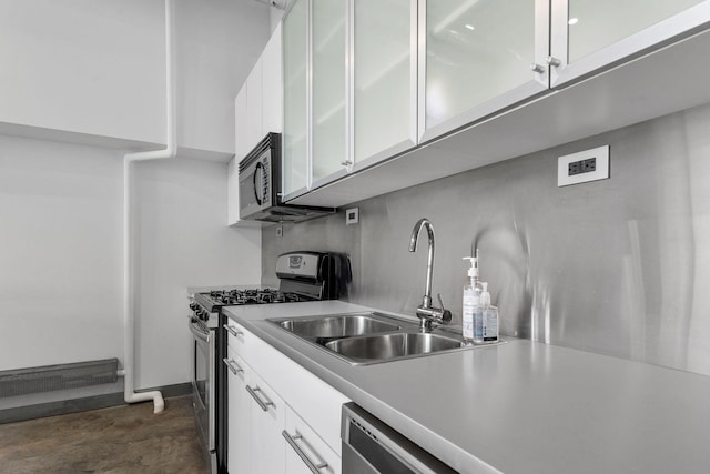 kitchen featuring light countertops, appliances with stainless steel finishes, a sink, and white cabinetry