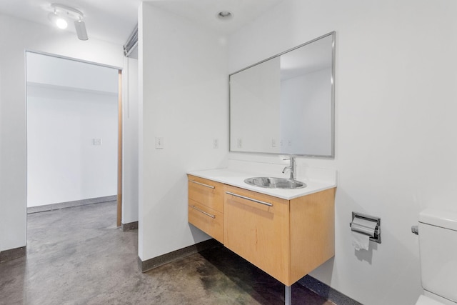 bathroom with toilet, baseboards, concrete flooring, and vanity