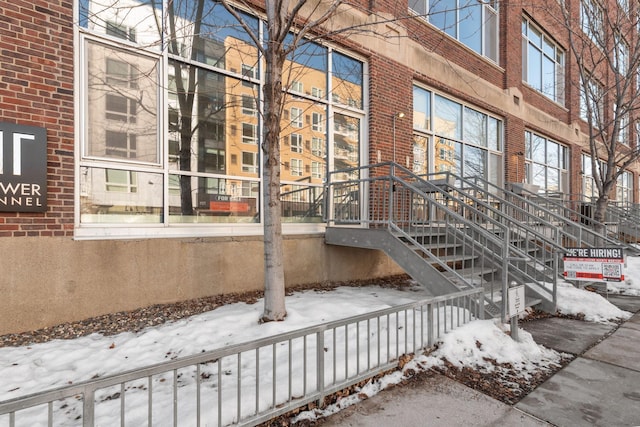 snow covered property entrance featuring brick siding